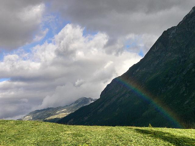 Ohne Heutrocknung keine Chance: frischgemähte Wiese mit Regenbogen bei Nufenen